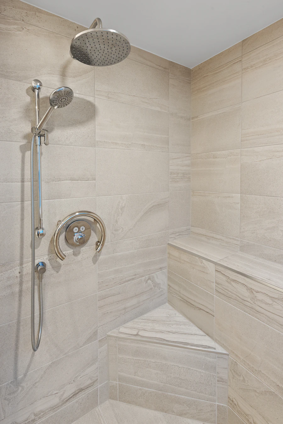 Walk-in tiled shower with a built-in bench, handheld shower and grab ring